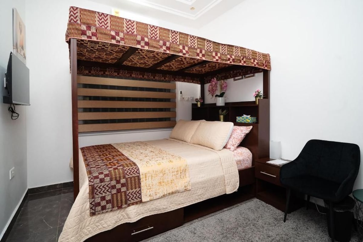 Un dormitorio con una cama, un escritorio, una silla y un televisor.