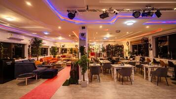 A spacious hotel lobby with seating areas, a red carpet, and a variety of plants.