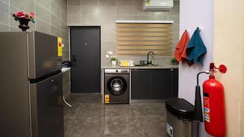 Cocina compacta equipada con refrigerador, lavadora, pileta y extintor de incendios.