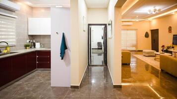 A modern kitchen with a marble floor, a dining area with a sofa and a table, and a hallway leading to another room.