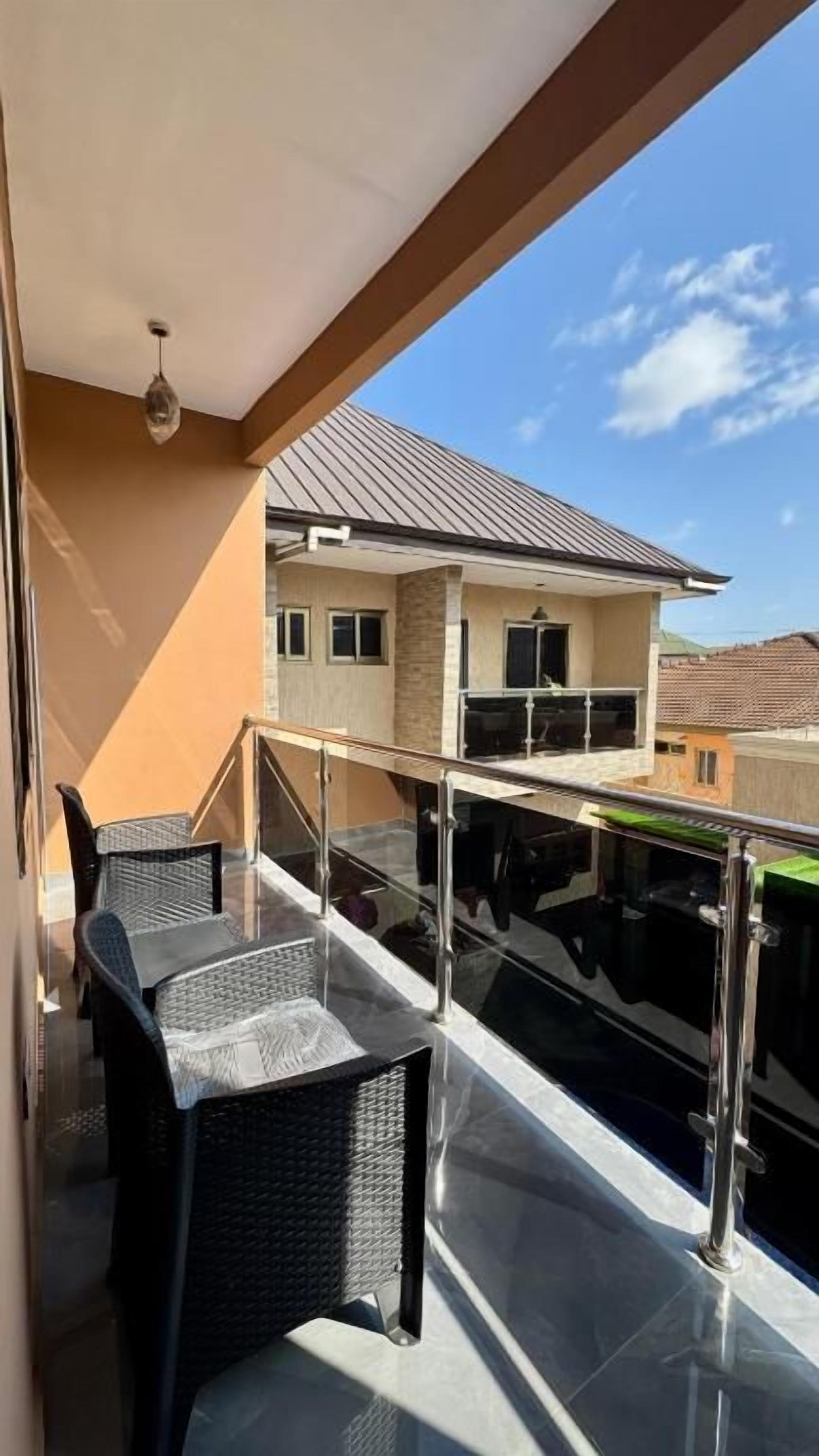 A balcony with a glass railing, a table, and chairs.