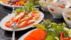 A buffet table with various dishes including sliced tomatoes, cucumbers, and leafy greens. - Hotel Rhein-ruhr (Bottrop)