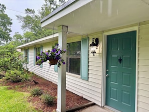 A house with a green door, a hanging flower basket, and a wall-mounted light fixture.