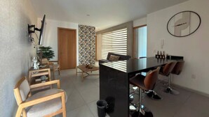 Um espaço de estar moderno com área de jantar, ilha de cozinha e sala de estar com cadeiras e sofá.