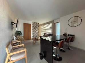 Ein moderner Wohnraum mit Essbereich, Kücheninsel und einer Sitzecke mit Sesseln und einer Couch.