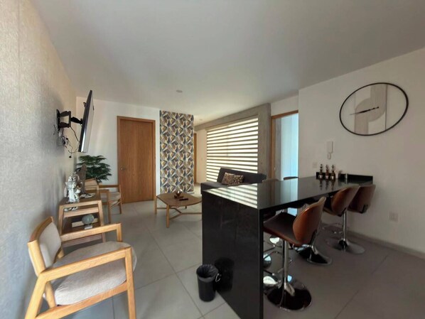 Ein moderner Wohnraum mit Essbereich, Kücheninsel und einer Sitzecke mit Sesseln und einer Couch.
