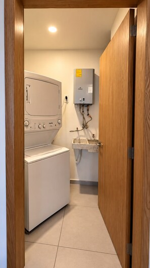 Une buanderie équipée d’un lave-linge, d’un chauffe-eau et d’un évier.