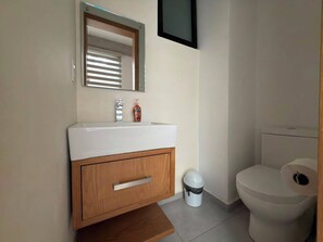Ein Badezimmer mit einem weißen Waschbecken, einem Holzschrank, einem Spiegel und einer Toilette.