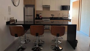 Uma cozinha moderna com uma ilha central, banquetas e um micro-ondas sobre o fogão.