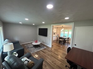 A living room with a sofa, a coffee table, and a TV mounted on the wall.