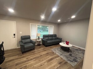 A living room with a gray sofa, a small round table, and a window with blinds. - Notre Dame stadium 17 mins. Sleeps 6 “ 5 star host” (South Bend)
