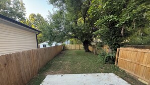 A backyard with a concrete patio, wooden fences, and trees. - Excellent 3-bedroom house with AC in cool Louisville neighborhood (Louisville)