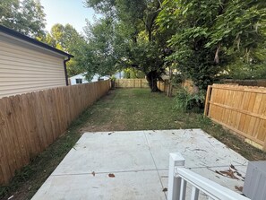 A backyard with a concrete patio, wooden fences, and trees. - Excellent 3-bedroom house with AC in cool Louisville neighborhood (Louisville)