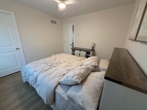Ein Schlafzimmer mit einem Bett, einem Nachttisch, einem Schreibtisch und einer Tür.