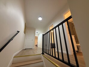 Eine Treppe mit schwarzer Geländer führt zu einem Raum mit Dusche.