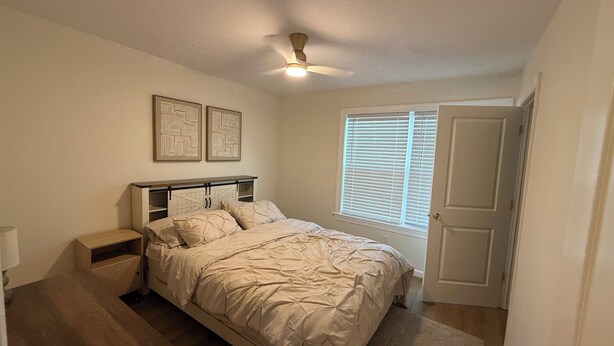 A bedroom with a bed, bedside tables, a ceiling fan, a window with blinds, and two wall-mounted pictures. - Excellent 3-bedroom house with AC in cool Louisville neighborhood (Louisville)