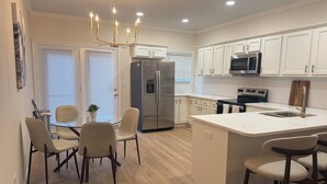 A modern kitchen with white cabinetry, stainless steel appliances, and a central island with bar stools. - Excellent 3-bedroom house with AC in cool Louisville neighborhood (Louisville)