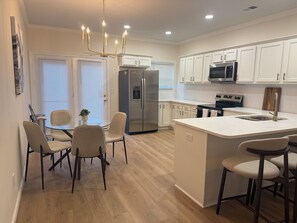 A modern kitchen with white cabinetry, stainless steel appliances, and a central island with bar stools. - Excellent 3-bedroom house with AC in cool Louisville neighborhood (Louisville)