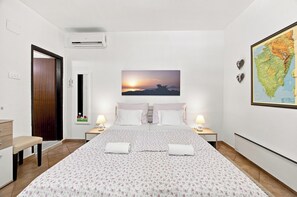 Ein Hotelzimmer mit einem Bett, zwei Nachttischen mit Lampen, einer Karte an der Wand und einer Klimaanlage.