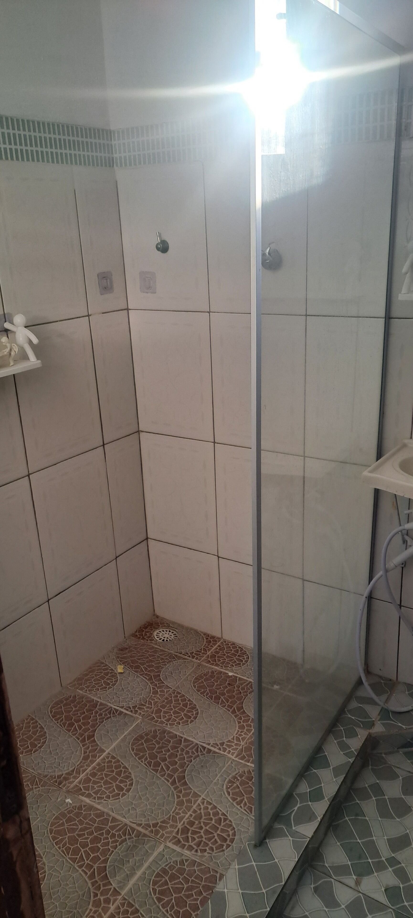 A small, tiled bathroom with a shower area, a toilet, and a sink.
