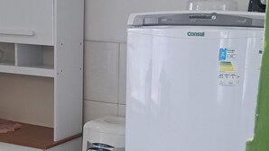 Eine Küche mit einem weißen Kühlschrank, einer weißen Waschmaschine und einem weißen Schrank mit Regalen.