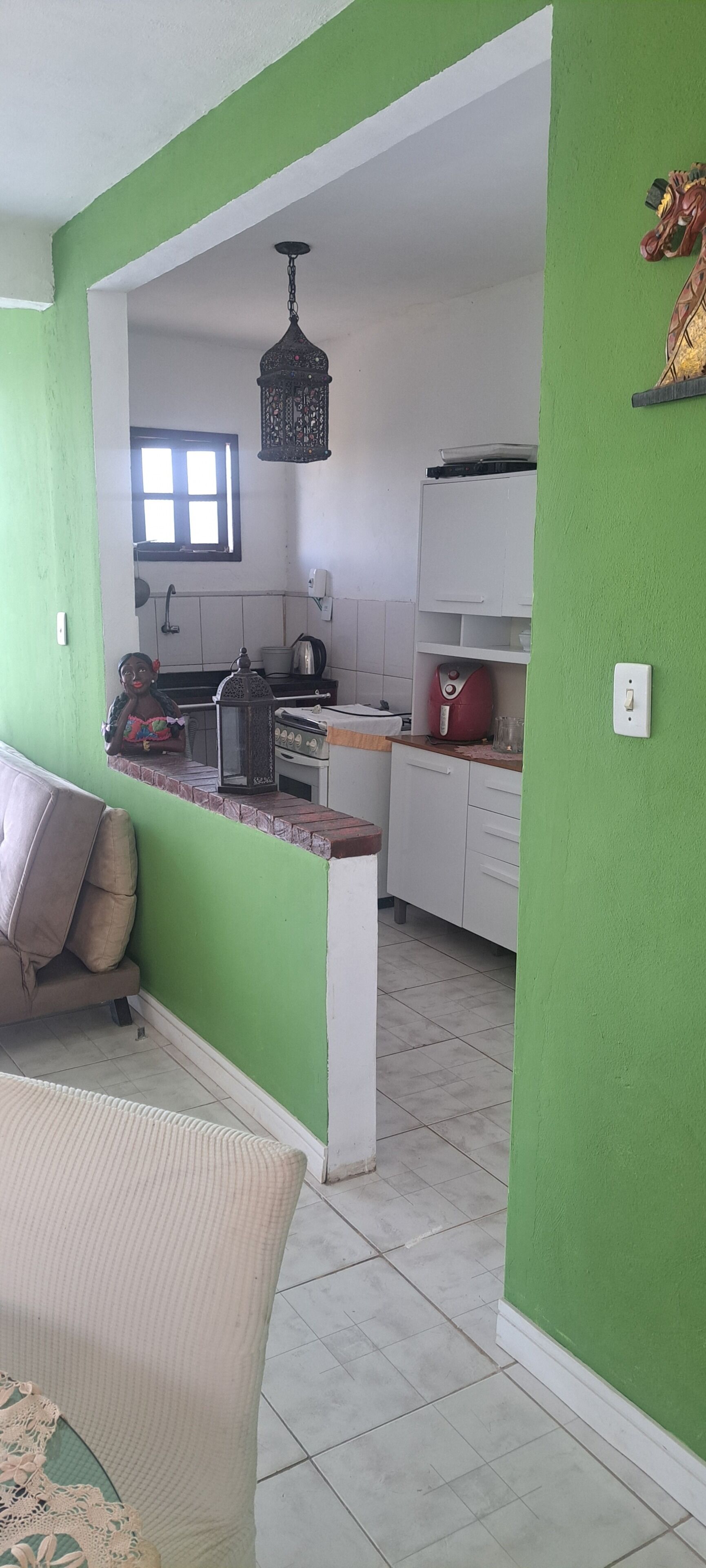 Cozinha com armários brancos, fogão e um candeeiro suspenso.