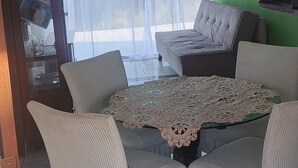 Ein Essbereich mit Tisch und Stühlen, einer Pendelleuchte und Blick durch große Fenster.