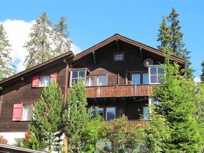 A two-story wooden building with balconies, surrounded by trees. - Chalet Waldesruh (3 ZWhg.) Appartement/Fewo, Badewanne, Komfort 4-Bettwohnung by Interhome (Arosa)