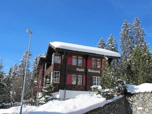 Ein Chalet mit schneebedecktem Dach, roten Fensterläden und der Aufschrift 'Chalet Waldersruh' an der Fassade.