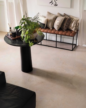A modern living room with a round black coffee table, a sofa with patterned cushions, and a potted plant on the table.