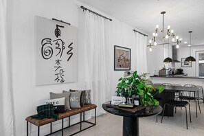 A modern interior with a dining area, a bench with cushions, a table with a plant, and a kitchen in the background.