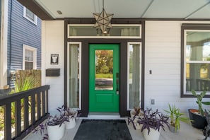 A green door with a star-shaped light fixture above it, a mailbox, and a small sign with the number 1177.