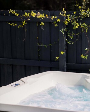 A hot tub with water, surrounded by a wooden fence with climbing plants. - The Slate Retreat | Pool + Hot Tub (Jacksonville)