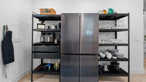 Een moderne keuken met een geïntegreerde roestvrijstalen koelkast, diverse opbergplanken en een scala aan keukengerei.