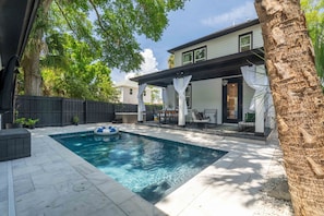Un jardin avec une piscine, un patio couvert et une maison.