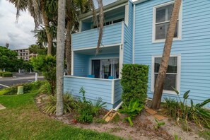 A two-story building with a balcony, surrounded by greenery and palm trees. - Salt + Sun | Beach + Pool (St. Augustine)