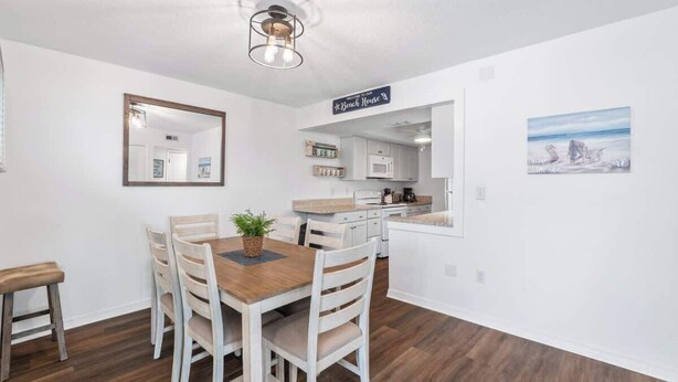 Een moderne keuken met witte kasten, een houten eettafel met stoelen en een hanglamp.