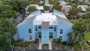 A two-story building with a flat roof, a central entrance, and a small parking area. - Salt + Sun | Beach + Pool (St. Augustine)