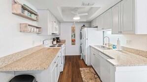Een moderne keuken met witte kasten, granieten werkbladen en een centraal eiland.