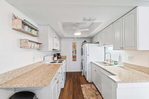 Eine moderne Küche mit weißen Schränken, Granit-Arbeitsplatten und einer Kochinsel.
