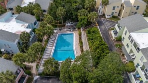 An aerial view of a residential area with a swimming pool surrounded by trees and houses. - Salt + Sun | Beach + Pool (St. Augustine)
