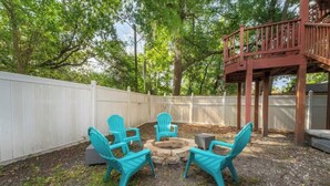A backyard with a fire pit and four turquoise chairs arranged around it. - Historic Gem in Springfield - Grill, Private Deck (Jacksonville)