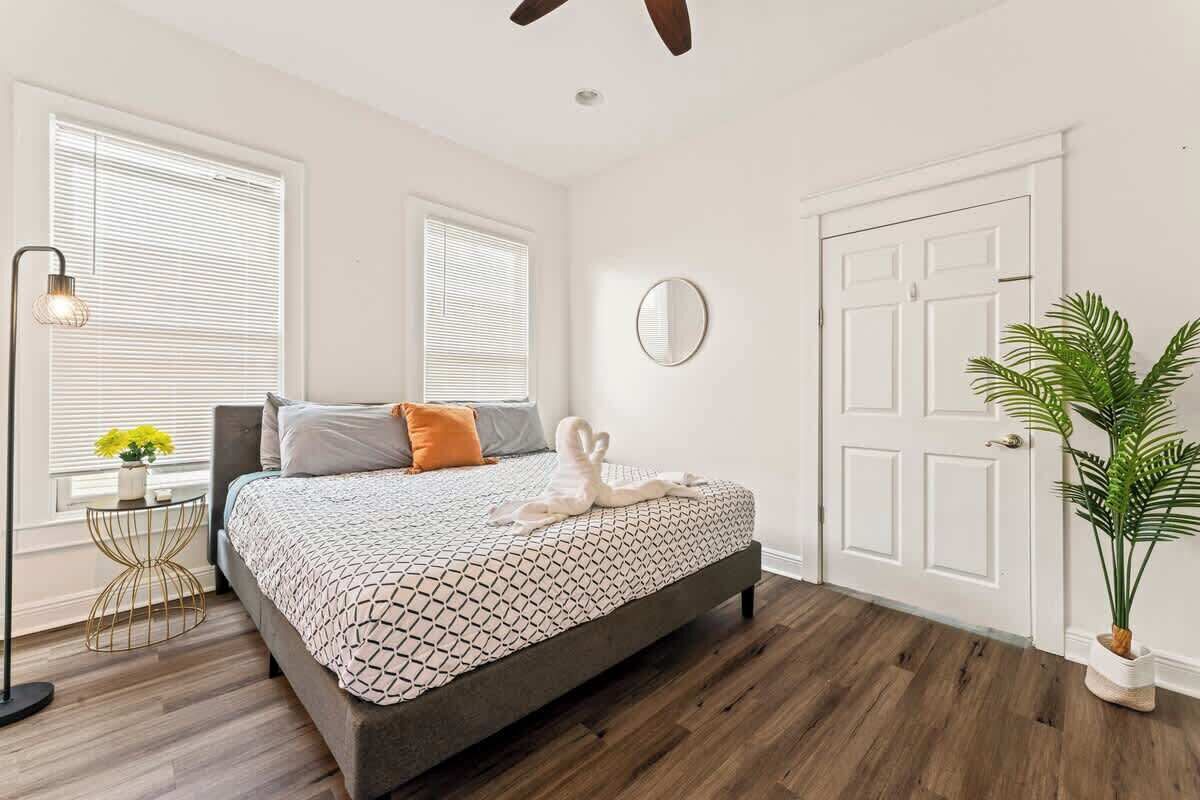 A bedroom with a bed, a round mirror, a potted plant, and a door.