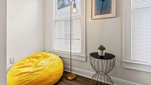 A room with a yellow bean bag chair, a floor lamp, a small table with a plant, and a framed picture on the wall. - Historic Gem in Springfield - Grill, Private Deck (Jacksonville)