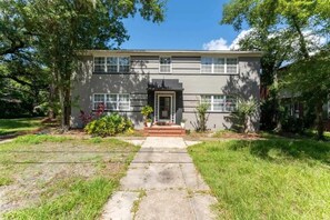 A two-story house with a front porch, a small garden, and a pathway leading to the entrance. - Eclectic Escape #1 | Team Joseph Ellen (Jacksonville)