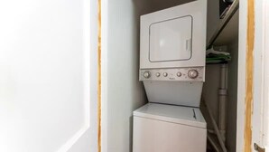 A compact laundry area with a washer and dryer stacked together. - Eclectic Escape #1 | Team Joseph Ellen (Jacksonville)