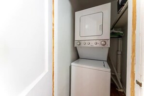 A compact laundry area with a washer and dryer stacked together. - Eclectic Escape #1 | Team Joseph Ellen (Jacksonville)