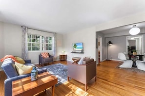 A living room with a sofa, coffee table, and a TV on the wall. - Eclectic Escape #1 | Team Joseph Ellen (Jacksonville)