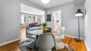 A modern living room with a glass dining table, a sofa, and a floor lamp. - Eclectic Escape #1 | Team Joseph Ellen (Jacksonville)