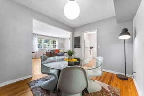 A modern living room with a glass dining table, a sofa, and a floor lamp. - Eclectic Escape #1 | Team Joseph Ellen (Jacksonville)